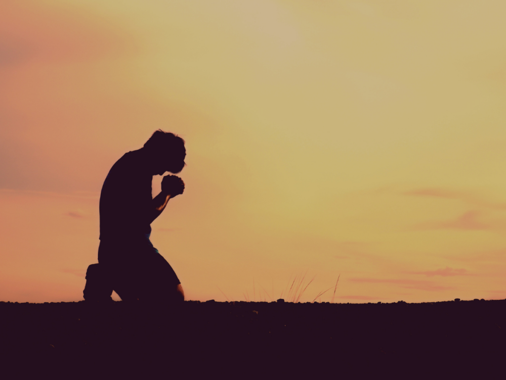 Silhouette of a man raising his hands in prayer